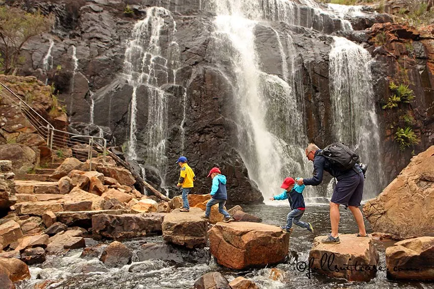 Father helping children to cross the river at MacKenzie Falls in The Grampians Australia