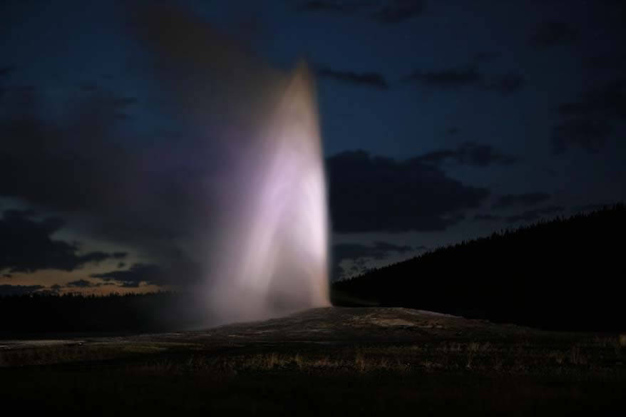 Old Faithful geyser at night