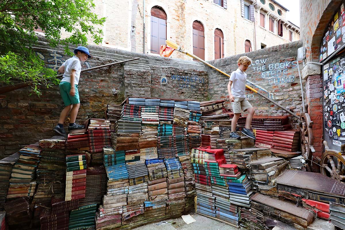 Kids walking on the book staircase in Libreria Acqua Alta in Venice