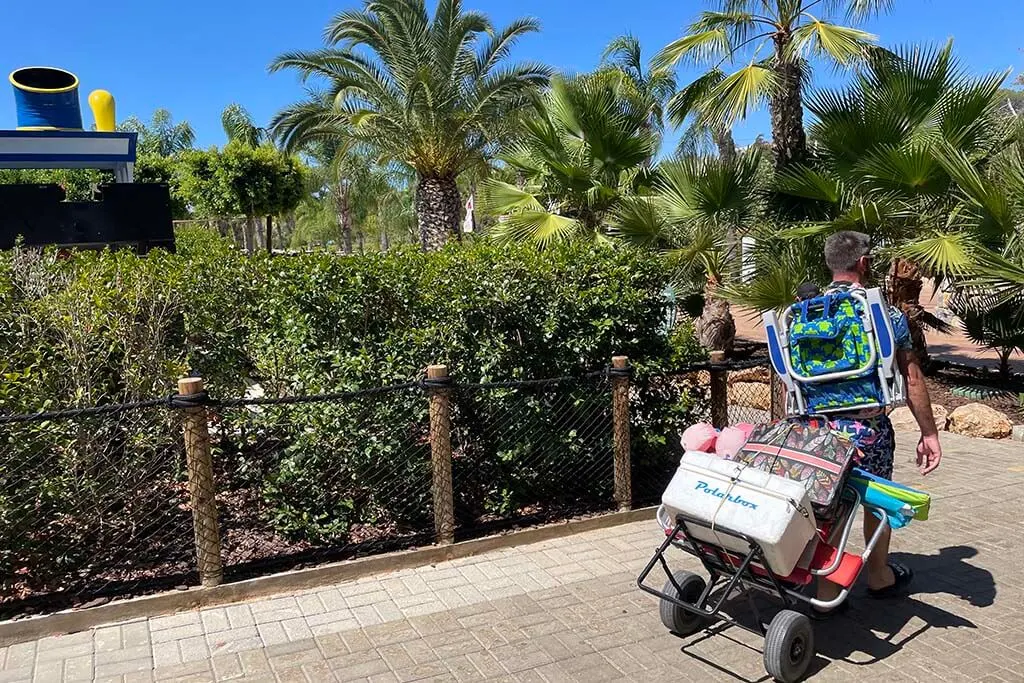 Man carrying beach chairs, umbrellas, and cooler box at Zoomarine Algarve