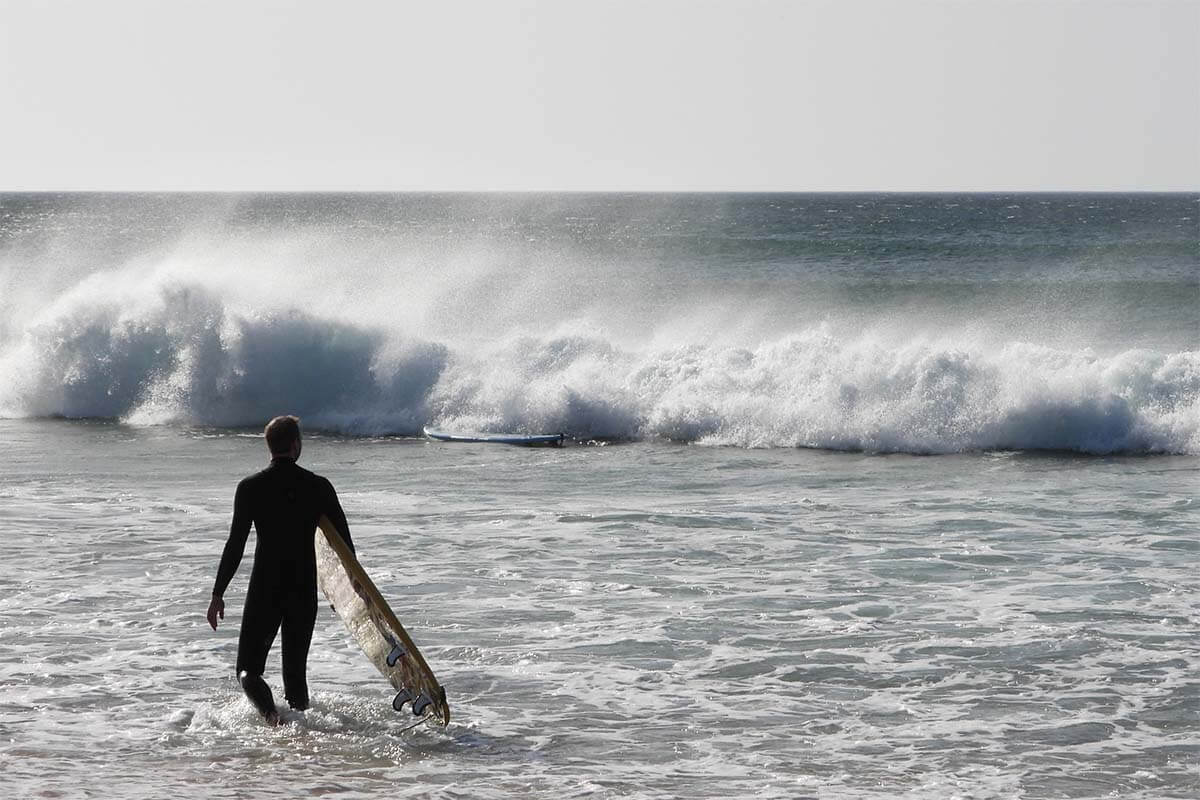 Surfer in the sea at Praia da Cordoama beach in Algarve Portugal